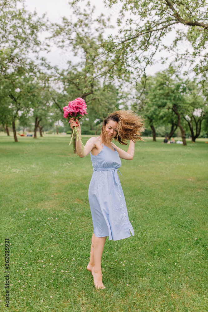 girl in the park with flowers peonies in a dress walks on the lawn girl in the park with flowers peonies in a dress walks on the lawn