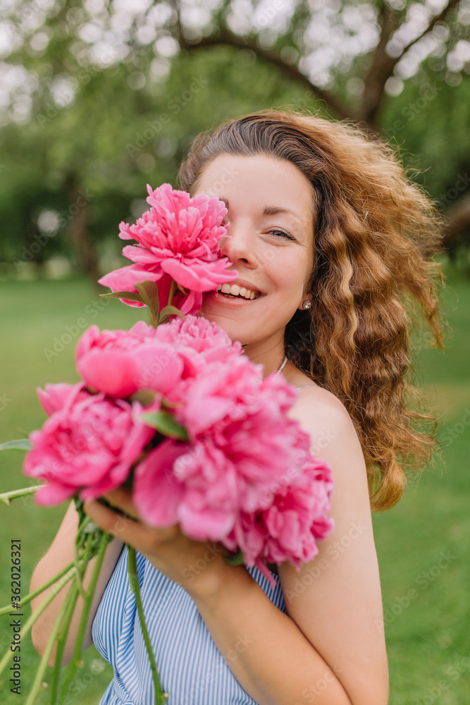 girl model mother on her head curly curls holding peonies and flowers in her dress gently presses them to herself on the nature in the park girl model mother on her head curly curls holding peonies and flowers in her dress gently presses them to herself on the nature in the park