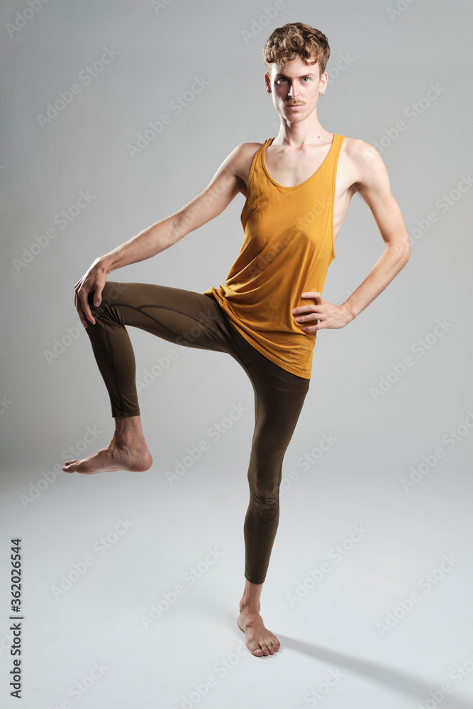 young blond boy with mustache and a yellow t-shirt balancing on one leg looking at camera young blond boy with mustache and a yellow t-shirt balancing on one leg looking at camera