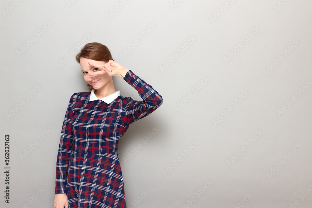 Portrait of cheerful girl showing victory or peace gesture near eye Portrait of cheerful girl showing victory or peace gesture near eye
