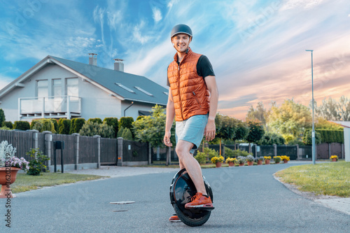 Young Man Stanging On Electric Unicycle (EUC) On Street, Best Mobile Portable Personal Transportation Vehicle, Summer Day photo