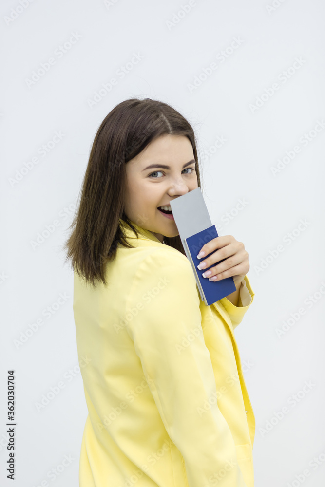 Young tourist woman looking at camera smiling and showing a passport and ticket to foreign country on white background. Young tourist woman looking at camera smiling and showing a passport and ticket to foreign country on white background.