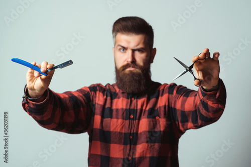 Brutal man holding proffecional tools. Barbershop advertising.