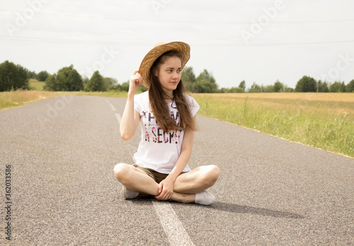 A woman sits on the road and looks away, travel theme, place for text.