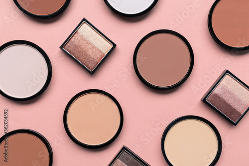 Cosmetic products for makeup on pastel pink background. Beige eyeshadow, blush and face compact powder for different skin colors concept. Trendy beauty pattern. Top view. Flat lay. Closeup. Tone cream