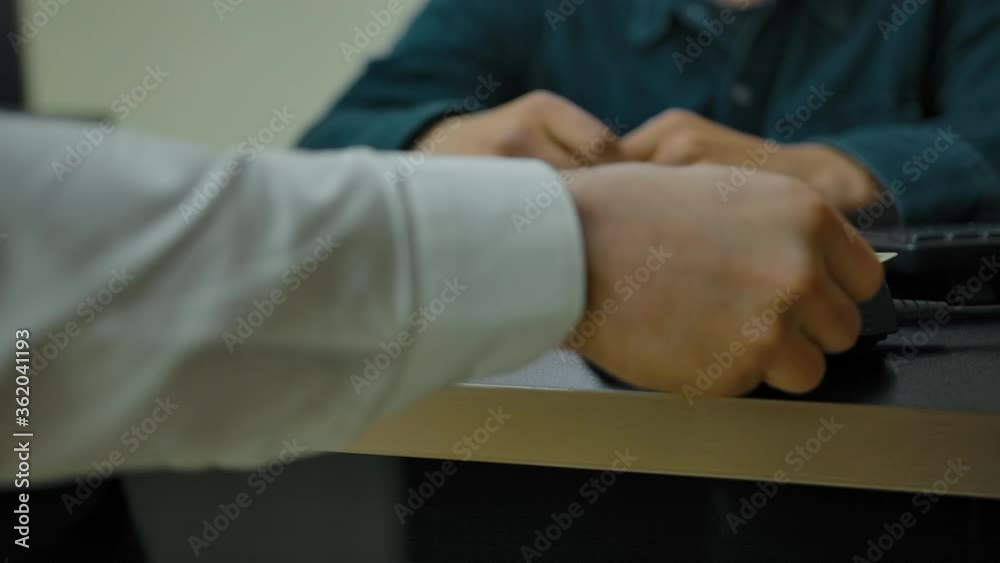 Payment by credit card via terminal in barbershop. Unrecognizable persons. Hand of a young man applies a plastic credit or debit card to the terminal for payment by bank transfer. Payment by credit card via terminal in barbershop. Unrecognizable persons. Hand of a young man applies a plastic credit or debit card to the terminal for payment by bank transfer.