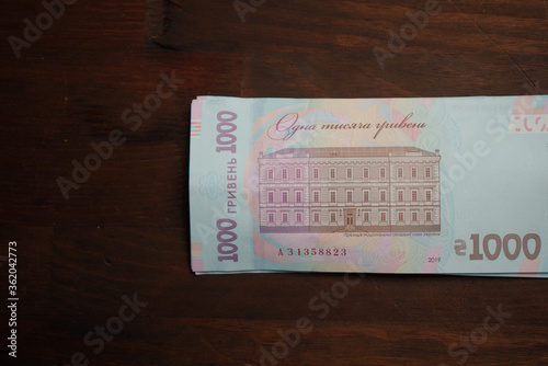 New Ukrainian paper money on wooden table. Reverse side of 1000 hryvnia bill. Cash money concept. Inflation concept. photo