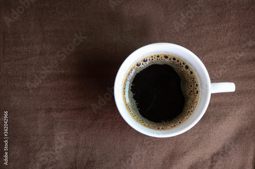 Black coffee is served on a brown bed to wake up in the morning.