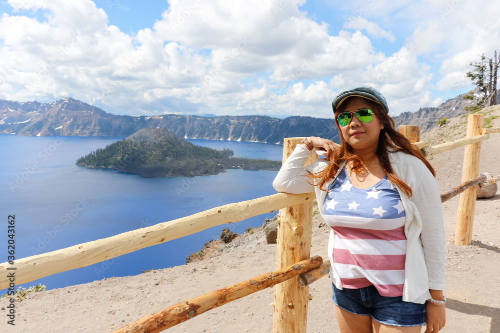 Asian women happy and enjoying a holiday trip to celebrate US Independence Day at Crater Lake, Oregon National Park.
