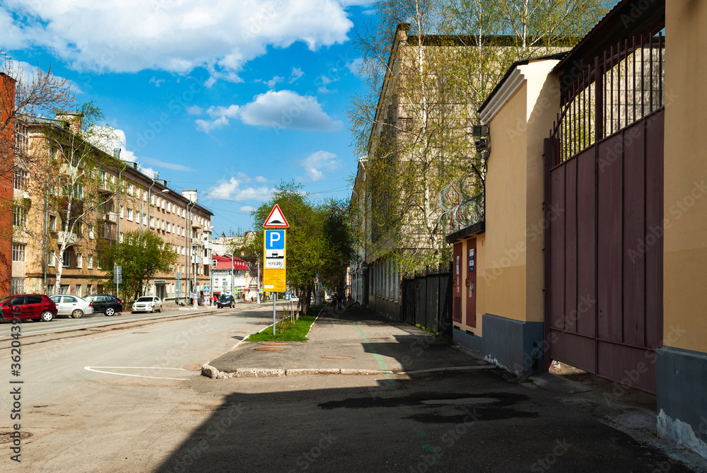 Obraz premium Free street. Street with roadway and sidewalks, on the sides of apartment buildings with parked cars. Clear sunny day, blue sky with white clouds