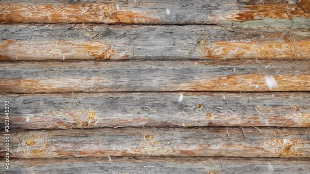 Falling snow on the background of a wooden log house. In winter, outdoors in the daytime. Round wooden logs connected by tow. Against the background of the wall, snow falls in large flakes. For relax. Falling snow on the background of a wooden log house. In winter, outdoors in the daytime. Round wooden logs connected by tow. Against the background of the wall, snow falls in large flakes. For relax.