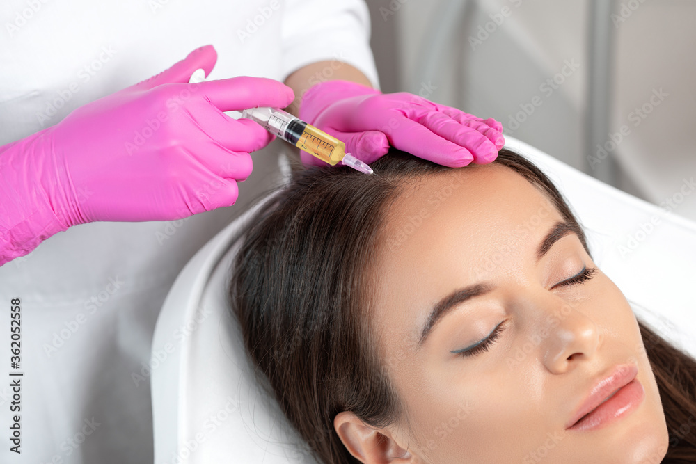 Fototapeta premium Cosmetologist does prp therapy against hair loss and anti-dandruff of a beautiful woman in a beauty salon. Cosmetology concept.