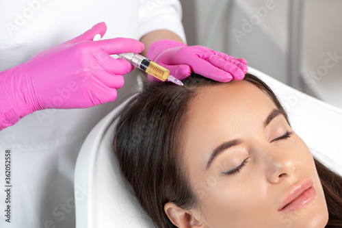 Cosmetologist does prp therapy against hair loss and anti-dandruff of a beautiful woman in a beauty salon. Cosmetology concept.