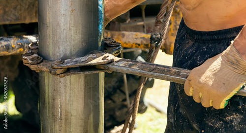 Schilderij op canvas Worker driller holds drill pipes with a huge key