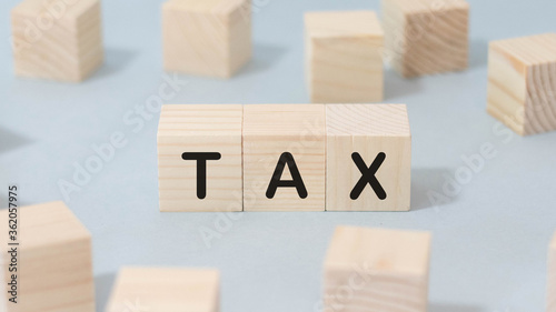 The word TAX on wooden cubes. on a blue background