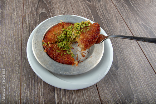 Turkish dessert kunefe, kunafa, kadayif with pistachio powder and cheese hot eaten a sweet. photo