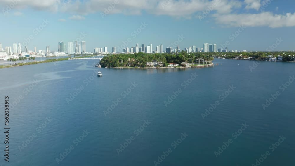 Camera approaching to the tropical island surrounded by the clear blue waters. 4K aerial stock video of lavish nature for travel business. Green island with Miami downtown on a background, Florida USA Camera approaching to the tropical island surrounded by the clear blue waters. 4K aerial stock video of lavish nature for travel business. Green island with Miami downtown on a background, Florida USA