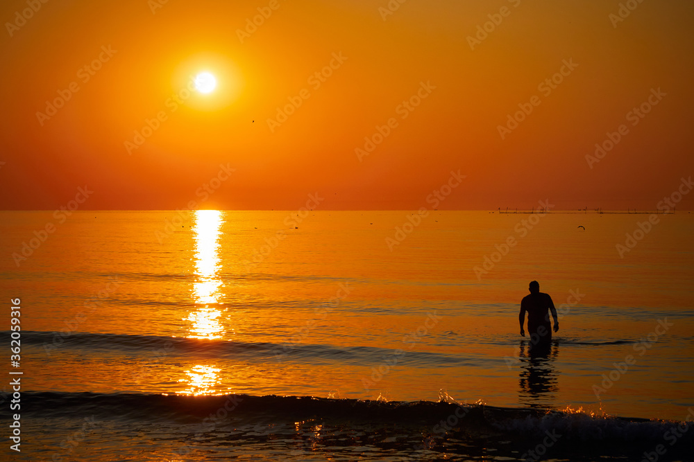 Silhouette of a man swimming in the sea at sunrise