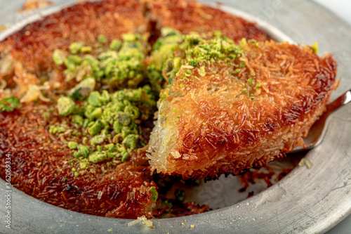 Turkish dessert kunefe, kunafa, kadayif with pistachio powder and cheese hot eaten a sweet. photo