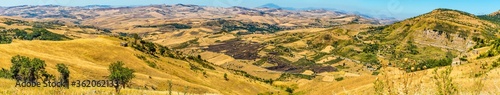 A panorama across the fields and hills of  the Madonie Mountains, Sicily with Mount Etna in the distance during summertime photo