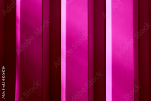 Element of the facade. Part of the facade decoration close-up. Facing material of buildings. Metal sheet roof. Pink color vertical sheet with shadow 