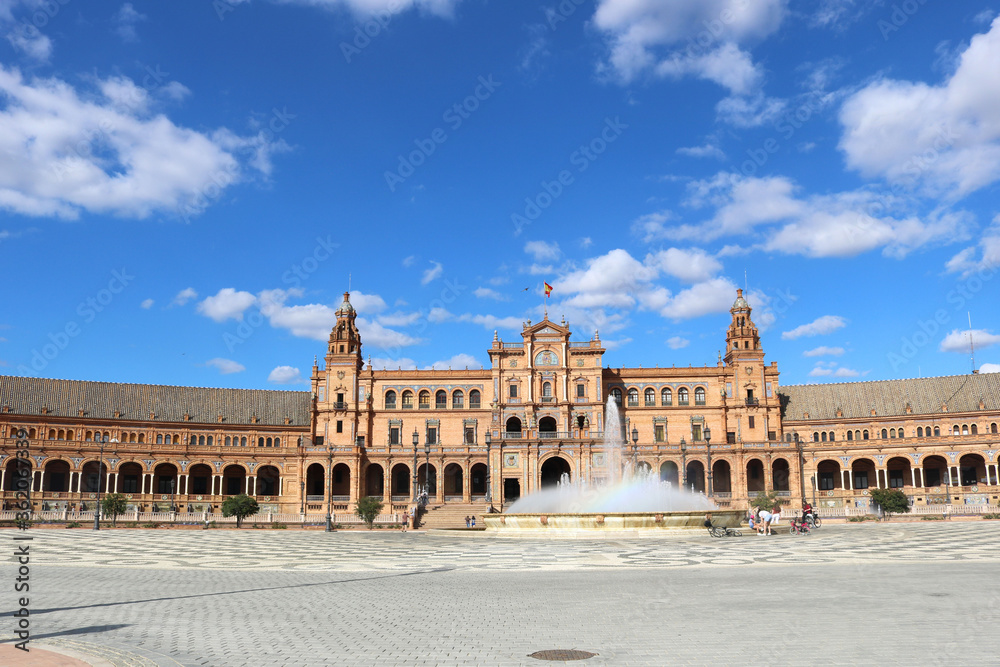 Square of Spain in Seville, with the main monument palace, the fountain and a blue sky with clouds in the background - horizontal postcard or wallpaper
