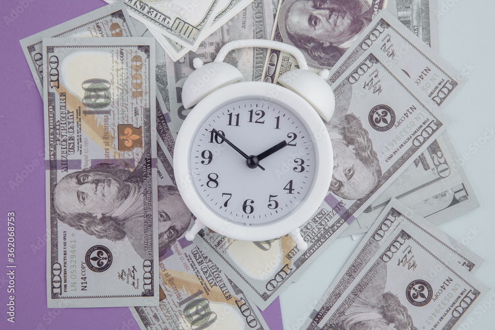Alarm clock on dollars banknotes on colorful background. Time is money concept. Alarm clock on dollars banknotes on colorful background. Time is money concept.