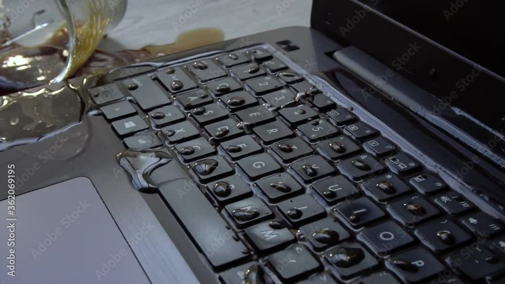 Coffee being spilled over laptop by accident. Keyboard is full of