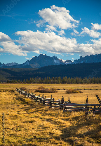 A split rail fence on the border of a large meadow with the Sawtooth mountains in the background  in the fall season near Stanley  Idaho.