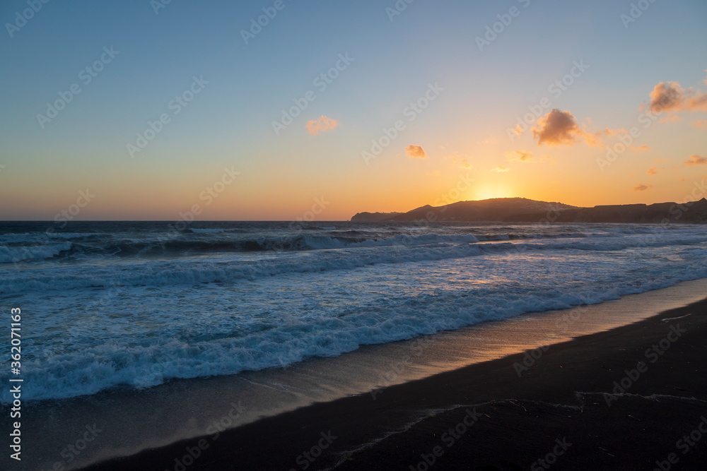 Beautiful coast at sunrise Vlychada beach on Santorini island in Greece. On the background of the sea is a blue sky with the rising sun. Beautiful coast at sunrise Vlychada beach on Santorini island in Greece. On the background of the sea is a blue sky with the rising sun.