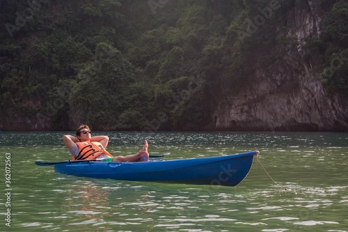 Happy man in a kayak boat on the lake. Relaxing in nature.