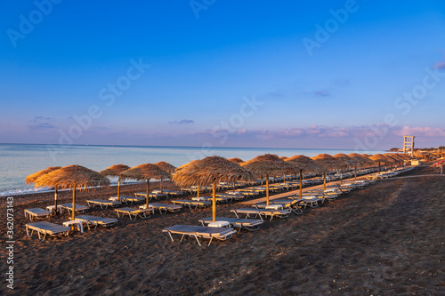 Fototapeta Naklejka Na Ścianę i Meble -  Perivolos beach on Santorini island in Greece at sunrise. The background is a blue sky with white clouds.