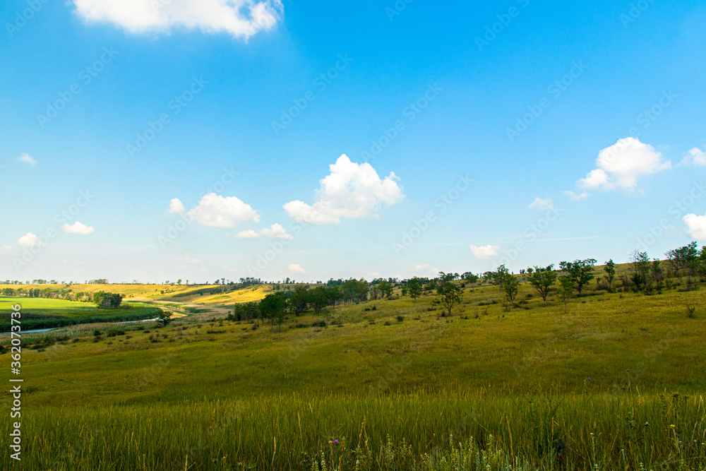 Fototapeta premium Beautiful view from the hill on the blue sky, the river and agricultural fields extending beyond the horizon.