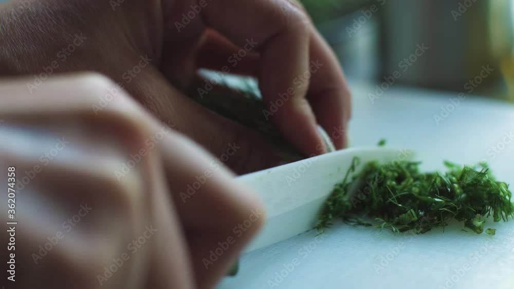 Slicing parsley on a white board, female hands taken from close up in slow motion. ProRES Slicing parsley on a white board, female hands taken from close up in slow motion. ProRES