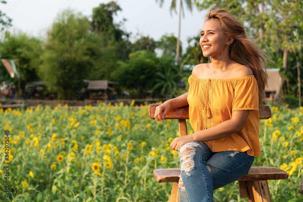 Young diverse woman sitting and smiling in afternoon with sunflower Young diverse woman sitting and smiling in afternoon with sunflower