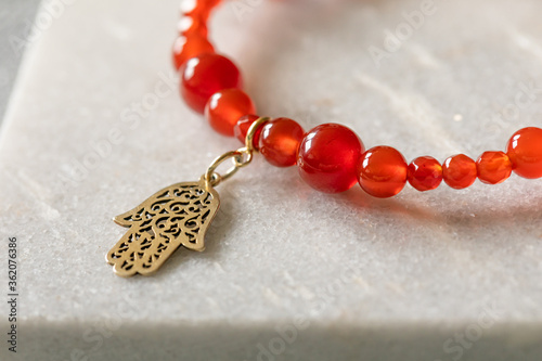 Tablou pe pânză Red bracelet made out of carnelian stone with a hamsa charm
