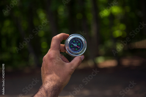 Traveler man holding a compass on forest