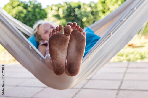 Photos Niña en una hamaca enseñando sus pies sucios después de haber jugado