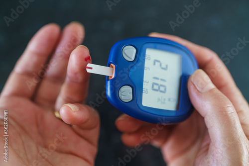 Medicine, Diabetes, Glycemia, Health care and people concept - close up of female using lancelet on finger to checking blood sugar level by Glucose meter photo