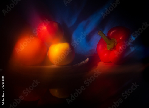 red pepper, orange and apple on blue background (art photography)