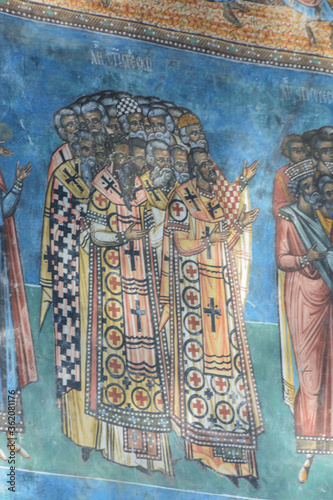 VORONET MONASTERY, BUCOVINA, ROMANIA, EUROPE, SPRING 2018. Back of the Orthodox Voronet Monastery with outdoor paintings and portraits of Byzantine-influenced saints. Moldovan architectural style.