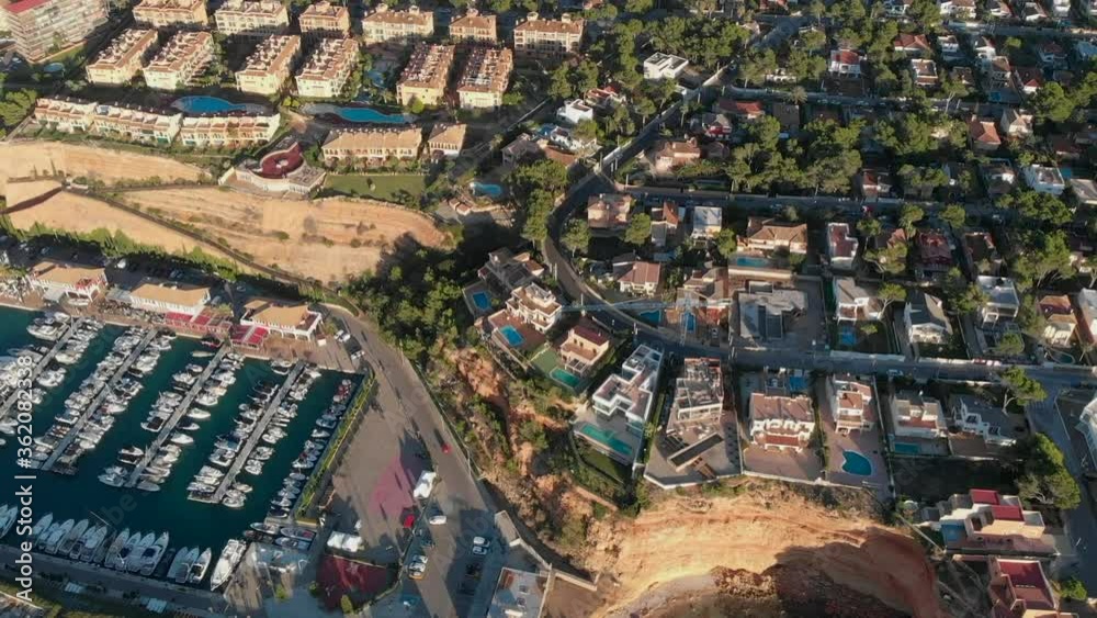 Aerial drone point of view Port Adriano docked yachts vessels in row, sunny summer day, residential villas modern luxury architecture view from above. Palma de Majorca, Balearic Islands. Spain