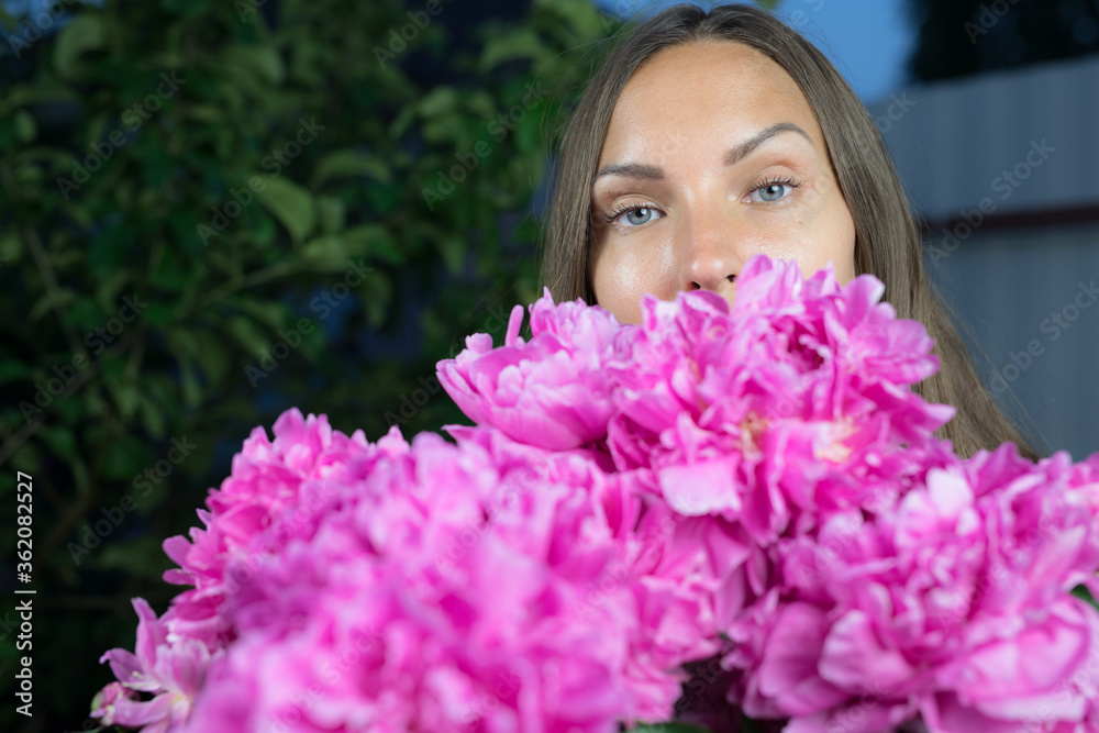 Young girl in evening garden enjoys bouquet of pink peonies. Young girl in evening garden enjoys bouquet of pink peonies.