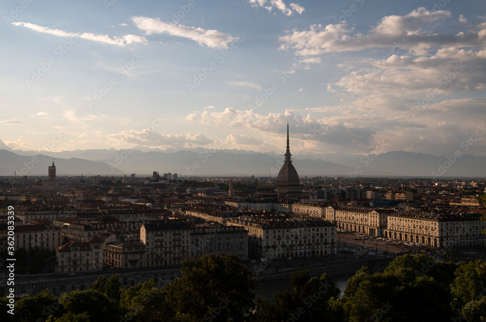 Foto di panorama urbano della città di Torino con vista montagne all'orizzonte e nuvole nel cielo.