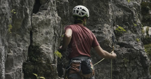 Climber ascend climb up high reach hand and attach clip lead rope in quickdraw carabiner chalk bag