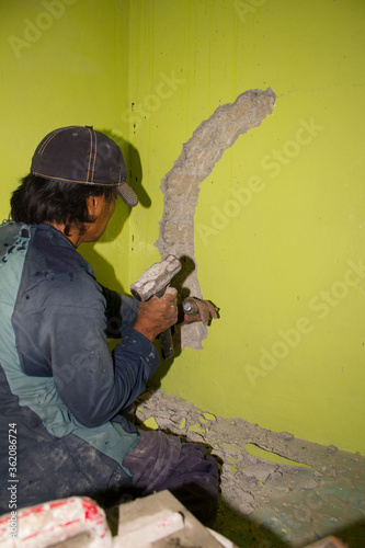 TRABAJADOR MARTILLANDO UNA PARED EN REPARACIÓN photo