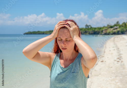 Obraz na płótnie Sunstroke on beach, woman with headache on vacation