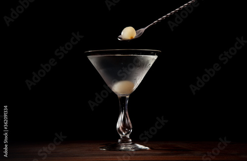 Gibson cocktail being finished with cocktail onions on a black background photo