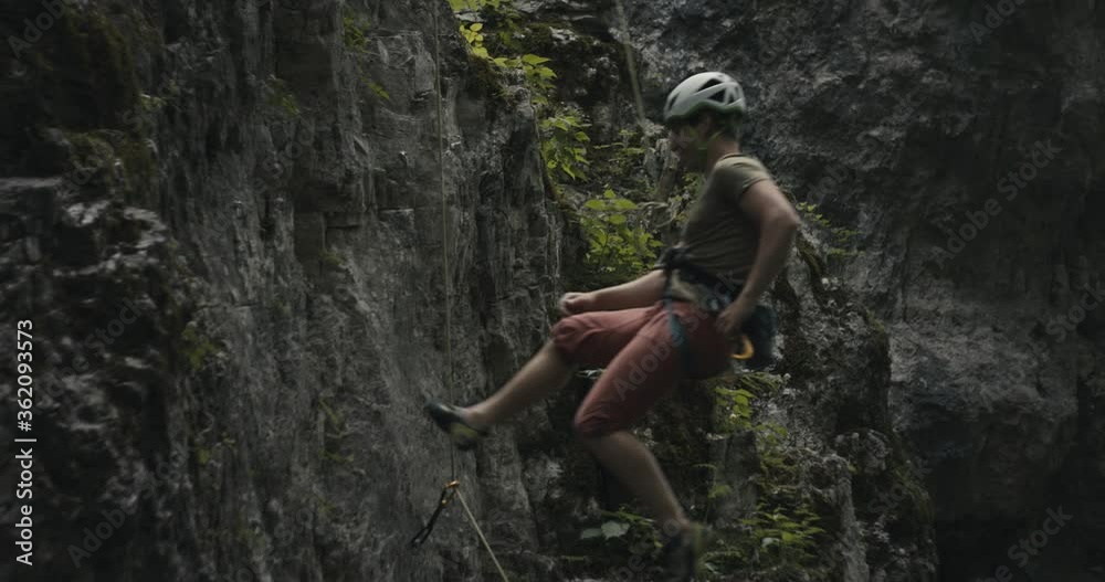 Climber finish climb descend rappel detach carabiner lead rope wear helmet protect by partner in stone rock wall Climber finish climb descend rappel detach carabiner lead rope wear helmet protect by partner in stone rock wall