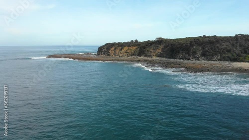 Forward moving aerial shot over calm ocean reef with cliffs on Australia's southern coast. photo